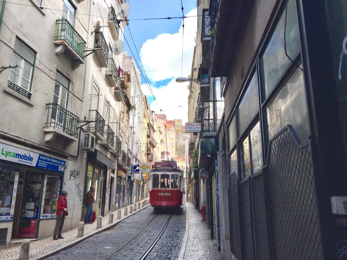 Historic yellow Tram 28 climbing through the Alfama district of Lisbon, Portugal